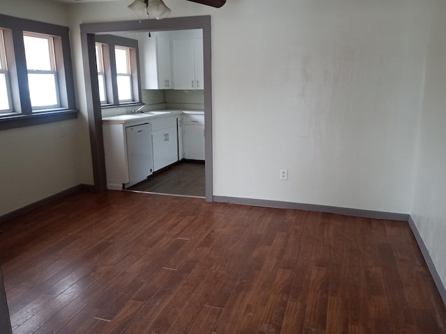 kitchen with white cabinetry, baseboards, light countertops, dishwasher, and dark wood finished floors