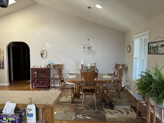 dining space with wood-type flooring, lofted ceiling, and an inviting chandelier