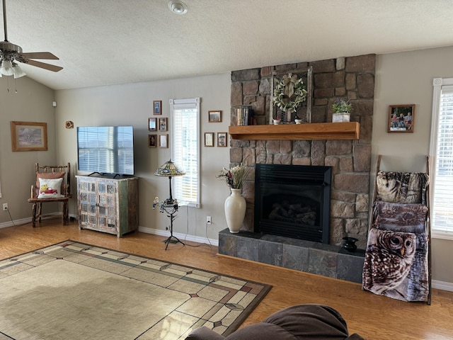 living room with ceiling fan, a fireplace, a healthy amount of sunlight, and a textured ceiling