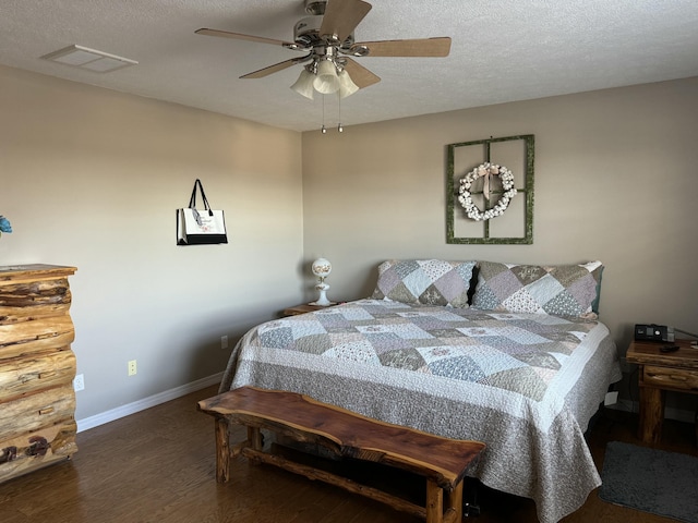 bedroom with a textured ceiling, ceiling fan, and dark wood-type flooring