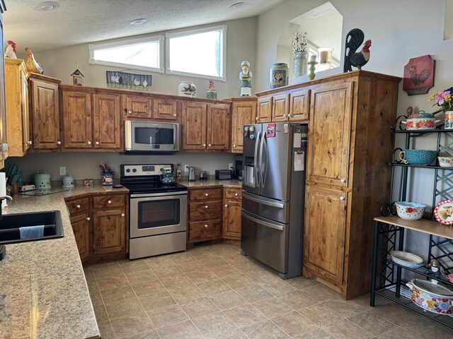 kitchen featuring a textured ceiling, sink, lofted ceiling, and appliances with stainless steel finishes