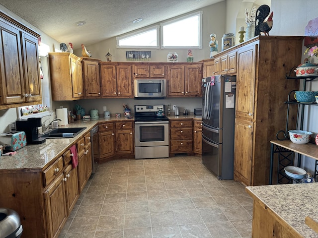 kitchen featuring a textured ceiling, sink, lofted ceiling, and appliances with stainless steel finishes