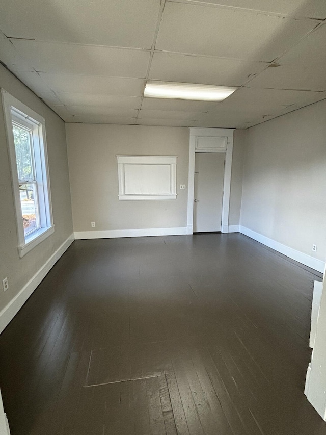 empty room featuring a drop ceiling and dark hardwood / wood-style flooring