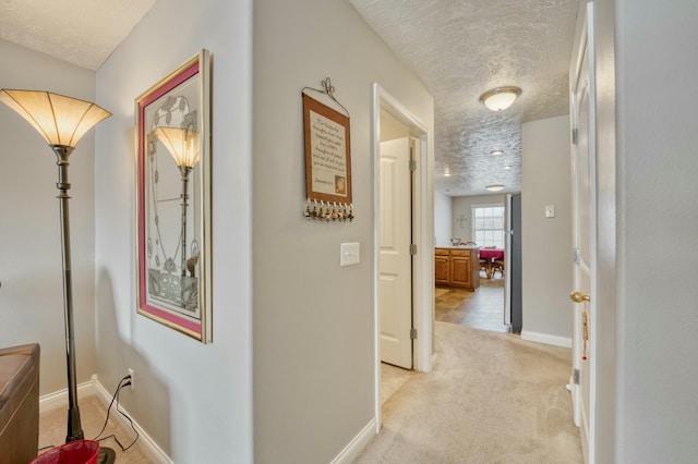 corridor featuring light carpet and a textured ceiling