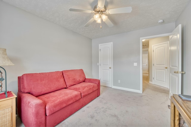 living room featuring ceiling fan, light carpet, and a textured ceiling