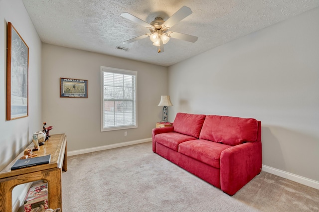 living room with ceiling fan, light colored carpet, and a textured ceiling