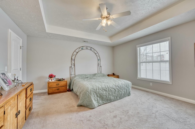 bedroom with a raised ceiling, ceiling fan, light carpet, and a textured ceiling