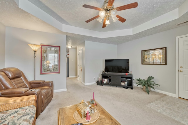 living room featuring a raised ceiling, light carpet, ceiling fan, and a textured ceiling