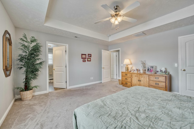 bedroom with a raised ceiling, ceiling fan, light colored carpet, and a textured ceiling