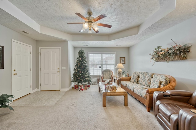 carpeted living room with ceiling fan, a raised ceiling, and a textured ceiling