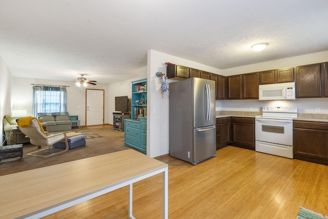 kitchen featuring dark brown cabinetry, white appliances, open floor plan, light countertops, and light wood-type flooring