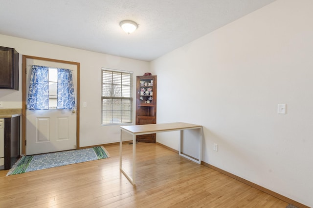 entryway with light wood-style floors, baseboards, and a textured ceiling