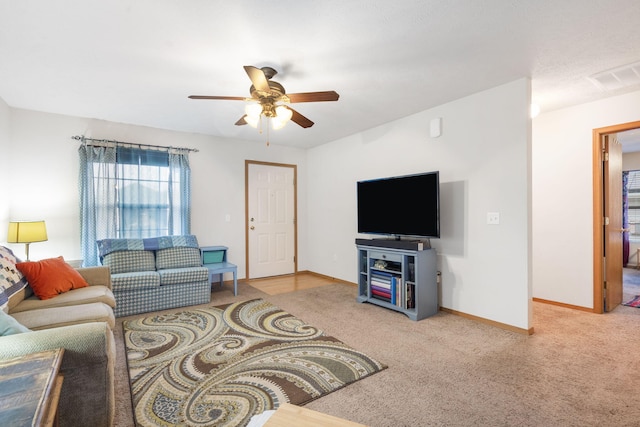 living area with light colored carpet, ceiling fan, visible vents, and baseboards