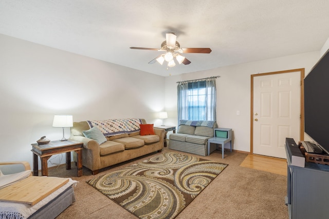 carpeted living area featuring a ceiling fan and baseboards