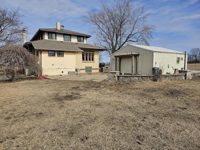 rear view of house with an outdoor structure and a patio area