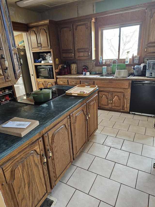 kitchen with light tile patterned floors, sink, black appliances, and tasteful backsplash