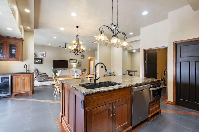 kitchen featuring dark stone countertops, beverage cooler, appliances with stainless steel finishes, and a sink