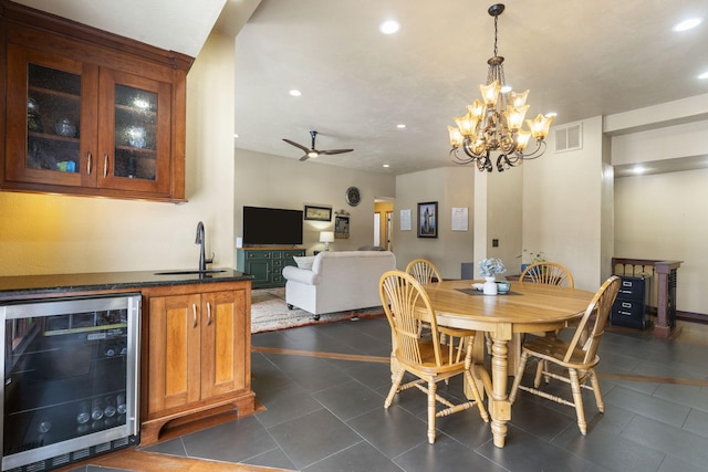 tiled dining space with sink, beverage cooler, and ceiling fan with notable chandelier