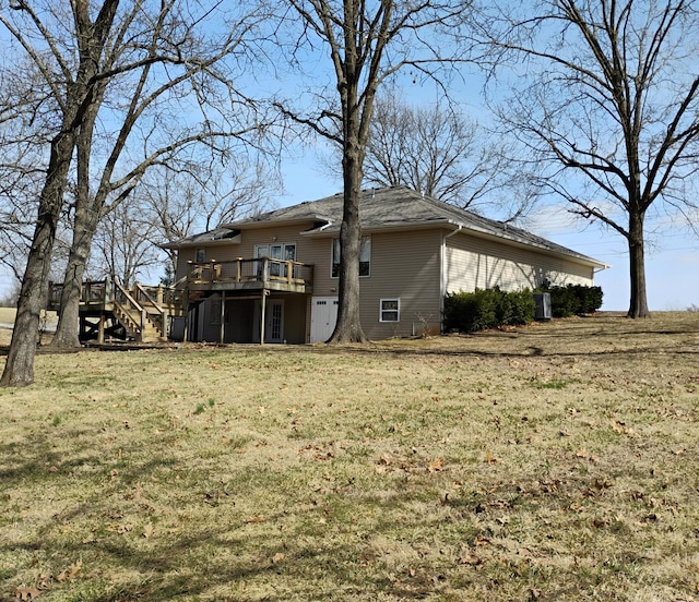 rear view of house featuring stairway, a wooden deck, and a lawn