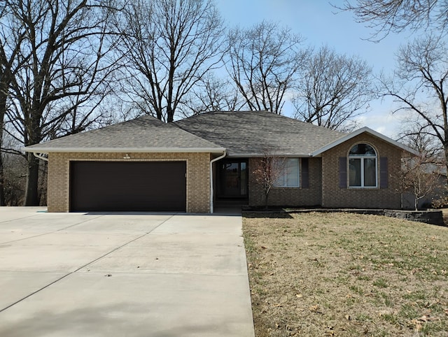 single story home with brick siding, a shingled roof, concrete driveway, a front yard, and a garage