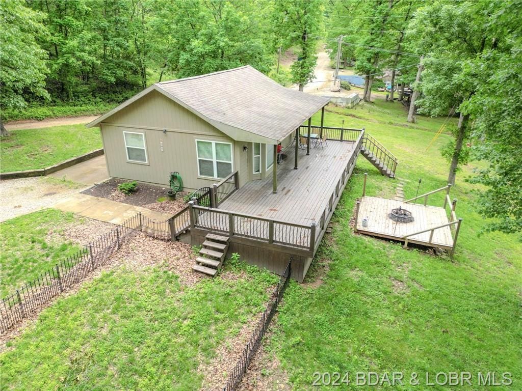 back of house featuring a lawn and a wooden deck