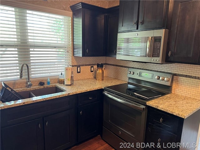 kitchen featuring light stone counters, sink, stainless steel appliances, and tasteful backsplash