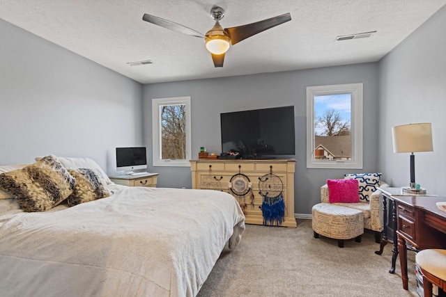 bedroom featuring visible vents, carpet flooring, a textured ceiling, and a ceiling fan