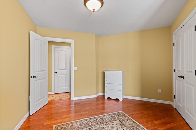 unfurnished bedroom with baseboards, a closet, and light wood finished floors
