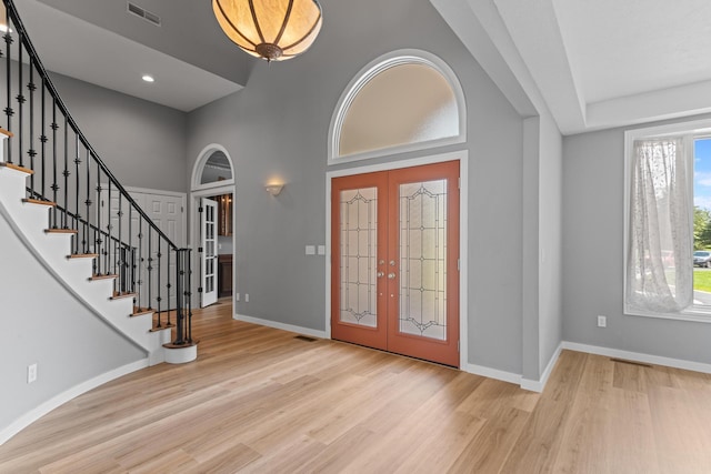 entryway featuring light wood finished floors, french doors, baseboards, visible vents, and stairway