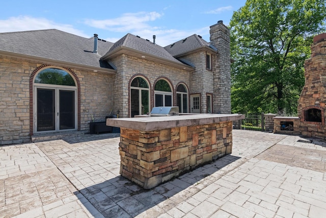 view of patio with a fireplace, a grill, and area for grilling
