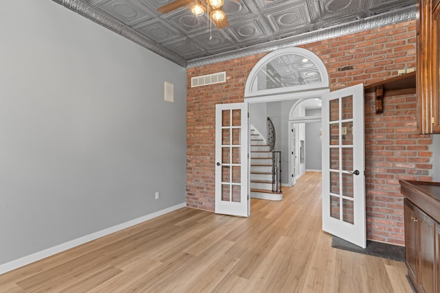 empty room featuring light wood-style floors, french doors, a ceiling fan, baseboards, and visible vents