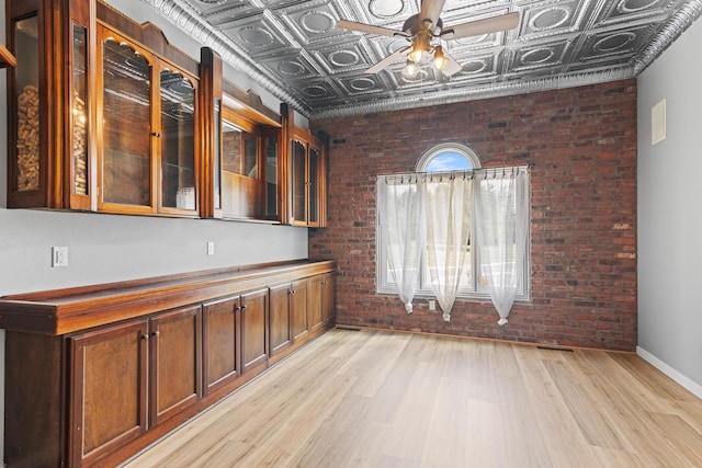 kitchen featuring an ornate ceiling, a ceiling fan, brick wall, and light wood finished floors