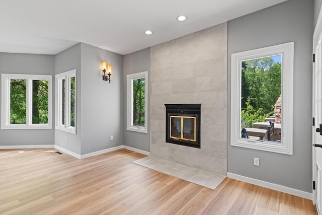 unfurnished living room featuring recessed lighting, baseboards, light wood-type flooring, and a tile fireplace