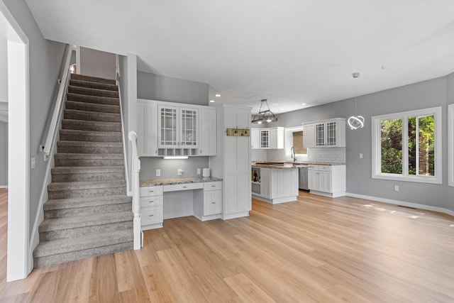 unfurnished living room with stairs, light wood-style floors, baseboards, recessed lighting, and a sink