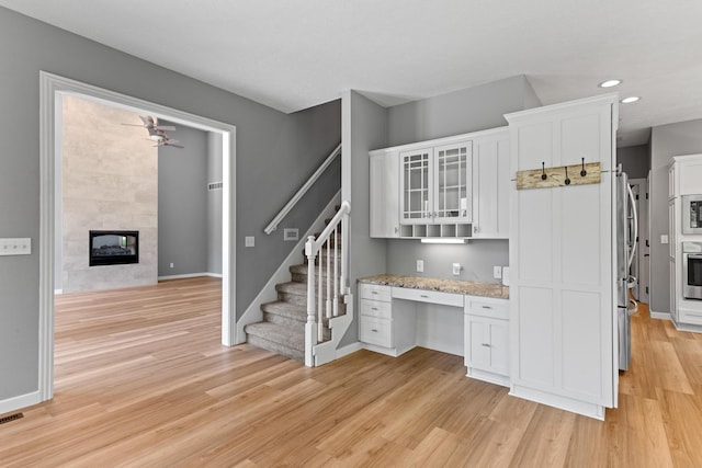 kitchen with white cabinets, light wood-style floors, stainless steel appliances, recessed lighting, and glass insert cabinets