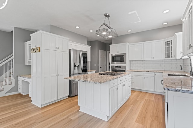kitchen featuring a sink, a kitchen island, stainless steel appliances, and white cabinets