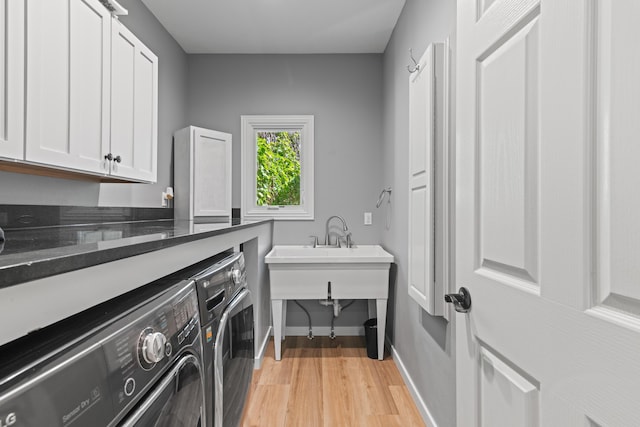 clothes washing area featuring baseboards, cabinet space, light wood-style flooring, and independent washer and dryer