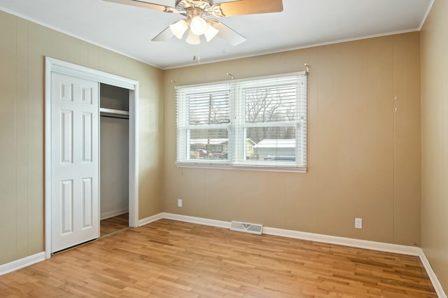 unfurnished bedroom with a closet, ceiling fan, crown molding, and light hardwood / wood-style flooring