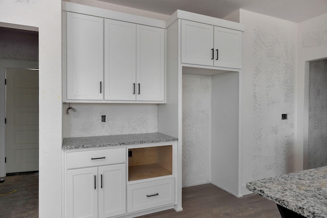 kitchen with dark hardwood / wood-style flooring, white cabinets, and light stone counters