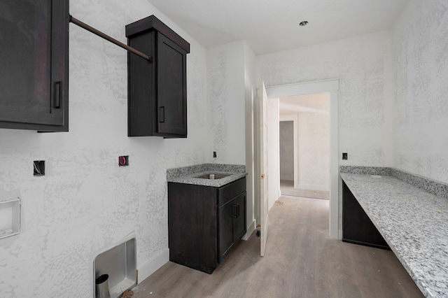 kitchen featuring light stone countertops, dark brown cabinetry, and light hardwood / wood-style flooring