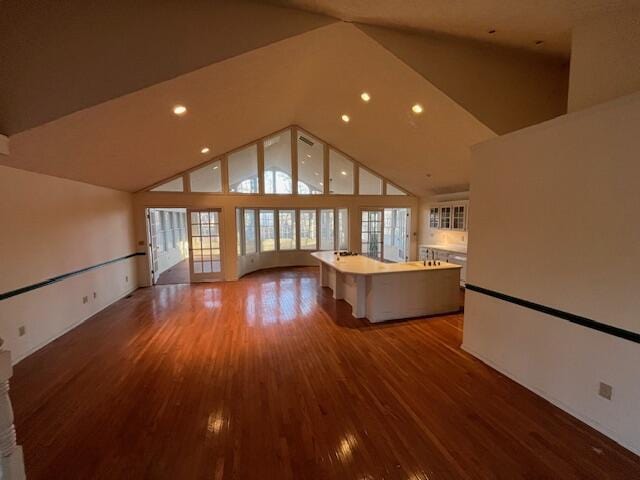 unfurnished living room featuring wood-type flooring and high vaulted ceiling