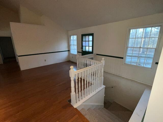 stairway with hardwood / wood-style floors and vaulted ceiling