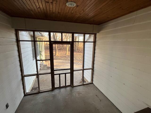 interior space featuring wooden ceiling, brick wall, and concrete floors