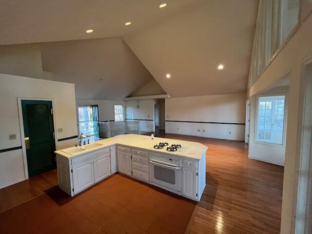 kitchen with white cabinetry, white appliances, sink, and high vaulted ceiling