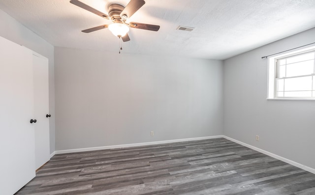 spare room featuring ceiling fan, dark wood-type flooring, and a textured ceiling