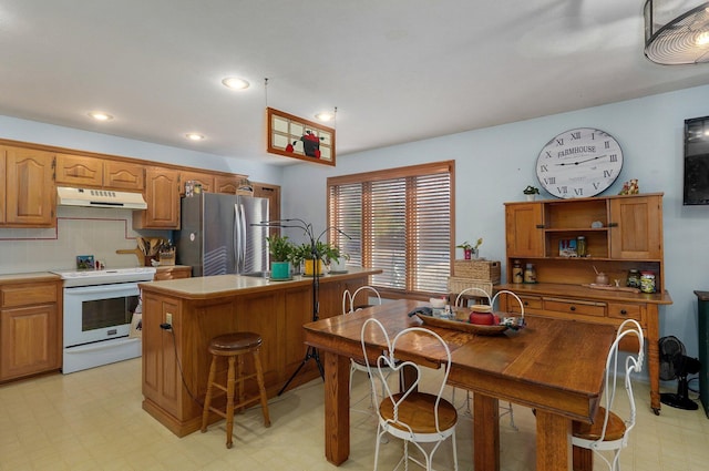 kitchen featuring a kitchen island, tasteful backsplash, white range with electric stovetop, and stainless steel refrigerator