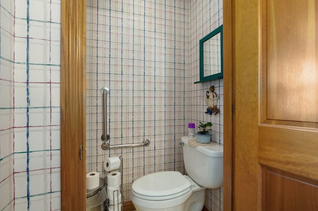 bathroom featuring toilet and tile walls