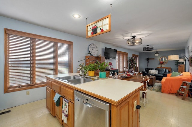 kitchen with stainless steel dishwasher, sink, and an island with sink