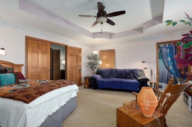 bedroom featuring ceiling fan, light carpet, and a tray ceiling