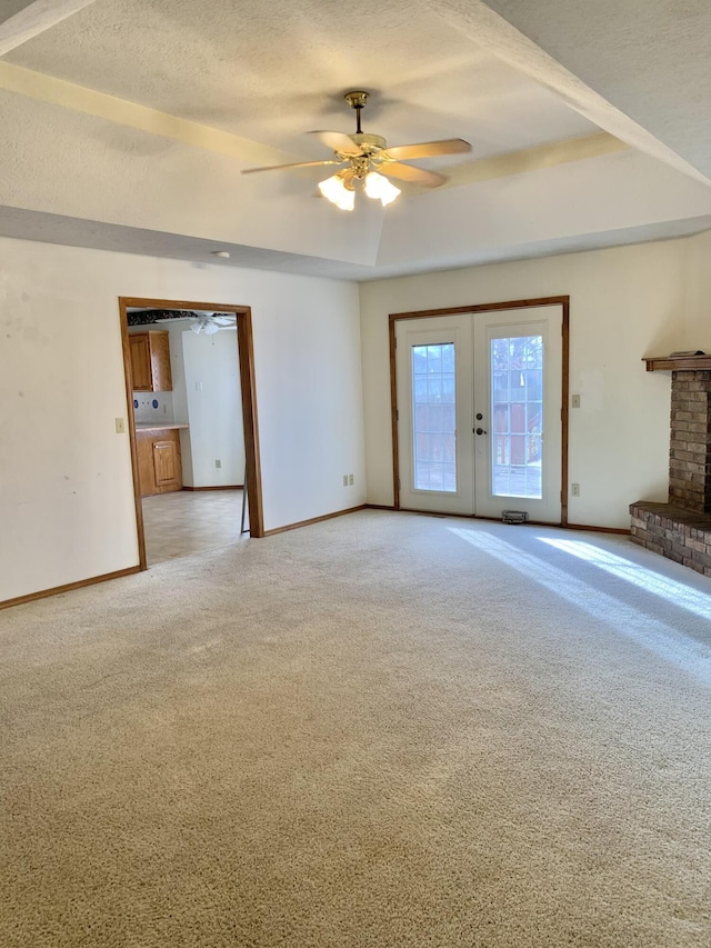 unfurnished living room featuring french doors, a textured ceiling, a raised ceiling, ceiling fan, and carpet floors